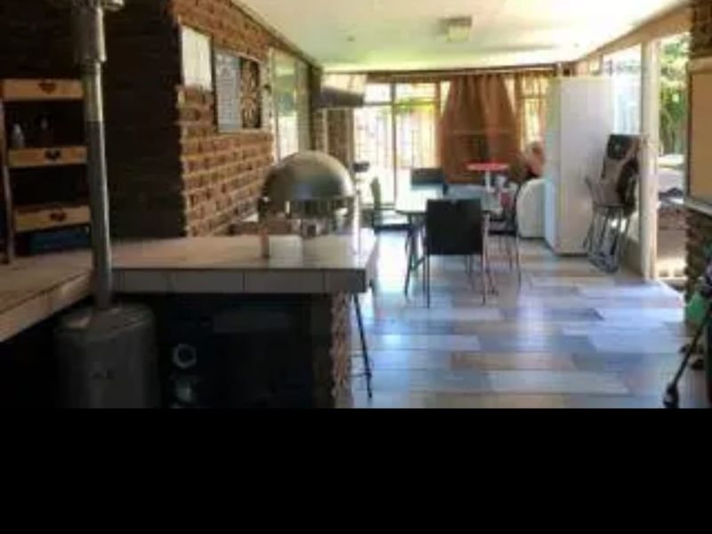 Covered patio area featuring exposed brick walls, tiled flooring, and a built-in bar counter, providing a functional space for outdoor entertaining.