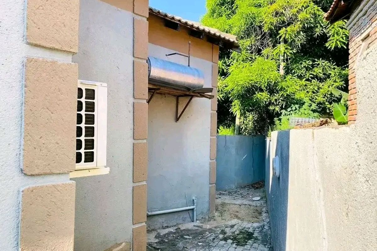 Side exterior area featuring a solar water heater, air conditioning unit, and paved pathway along the boundary wall.