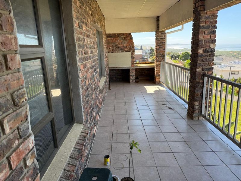 Covered balcony featuring brick pillars, tiled flooring, and a built-in braai area with scenic views.