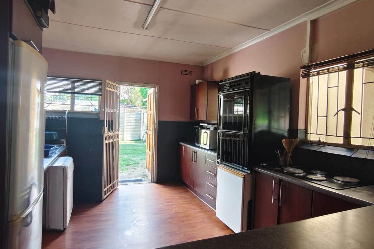 Functional kitchen featuring built-in cabinetry, integrated oven and hob, laminate countertops, and direct access to the rear garden through a security gate.