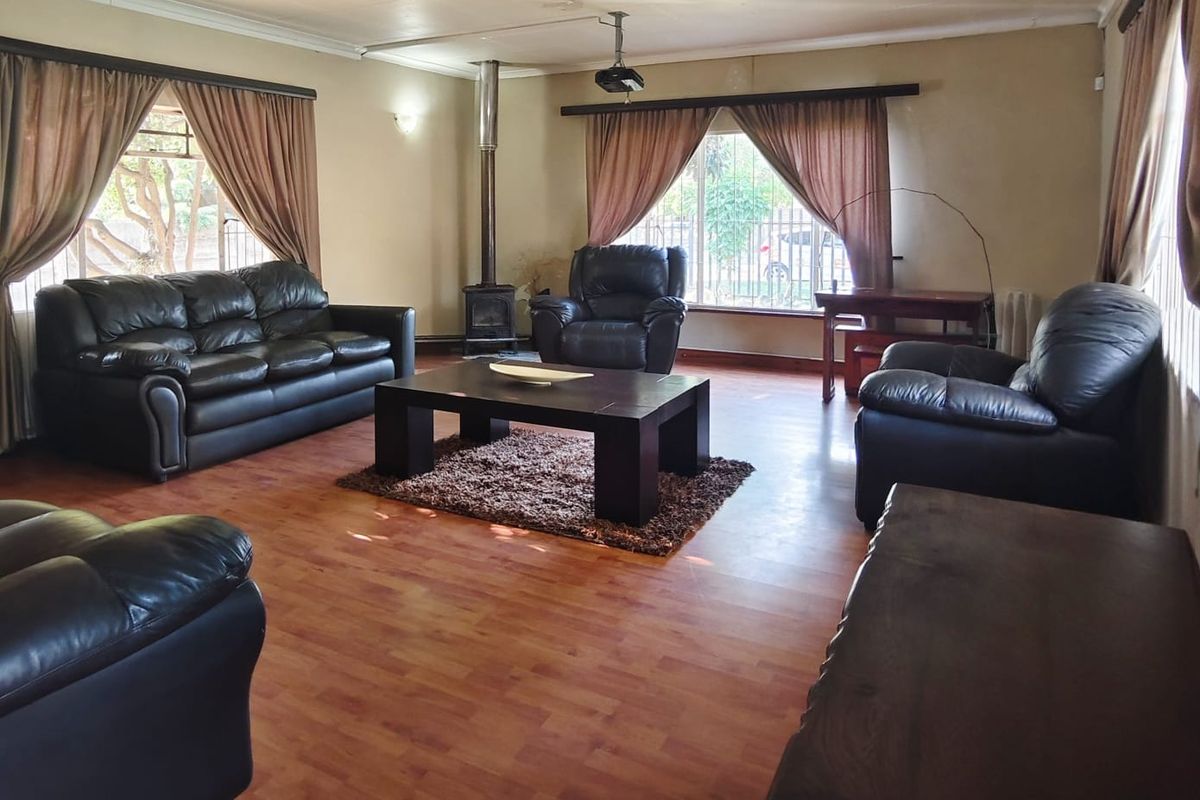 Spacious living room featuring laminate flooring, a wood-burning fireplace, and a ceiling-mounted projector, requiring some ceiling maintenance and cosmetic updates.
