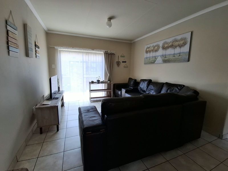 A living room featuring tiled flooring and a sliding glass door providing access to the exterior.
