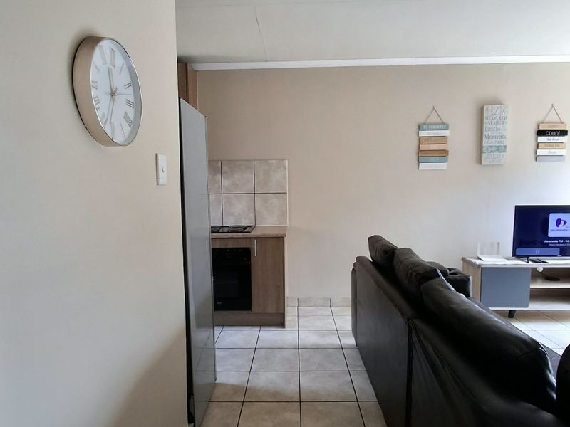 Open plan living area featuring tiled flooring and a compact kitchen corner with built-in oven and hob.