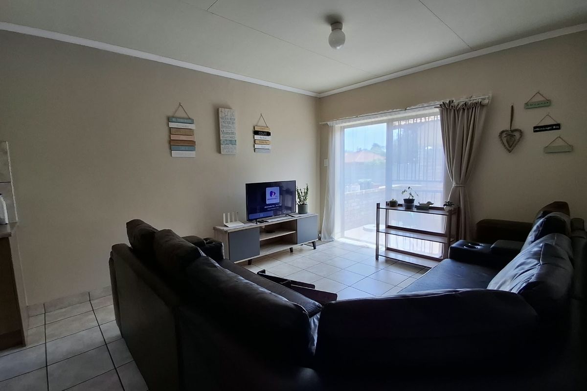 A comfortable living room featuring tiled flooring and a large sliding glass door that provides natural light and access to the outdoor area.
