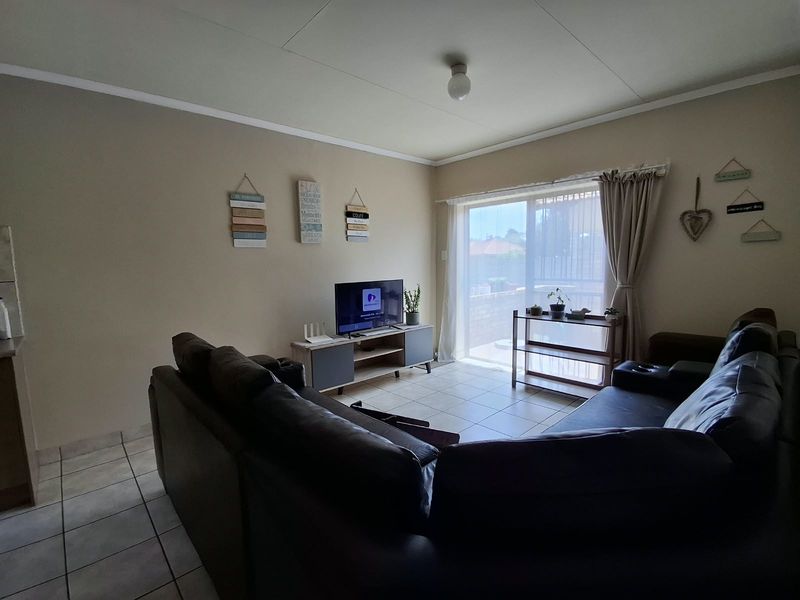 A comfortable living room featuring tiled flooring and a large sliding glass door that provides natural light and access to the outdoor area.