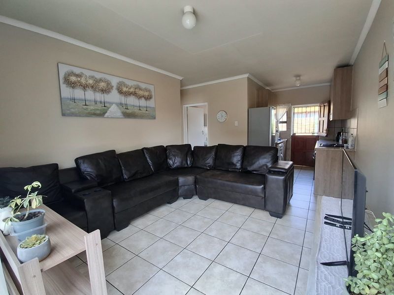 Open-plan living area featuring tiled flooring and a functional kitchen layout with direct access to the exterior.