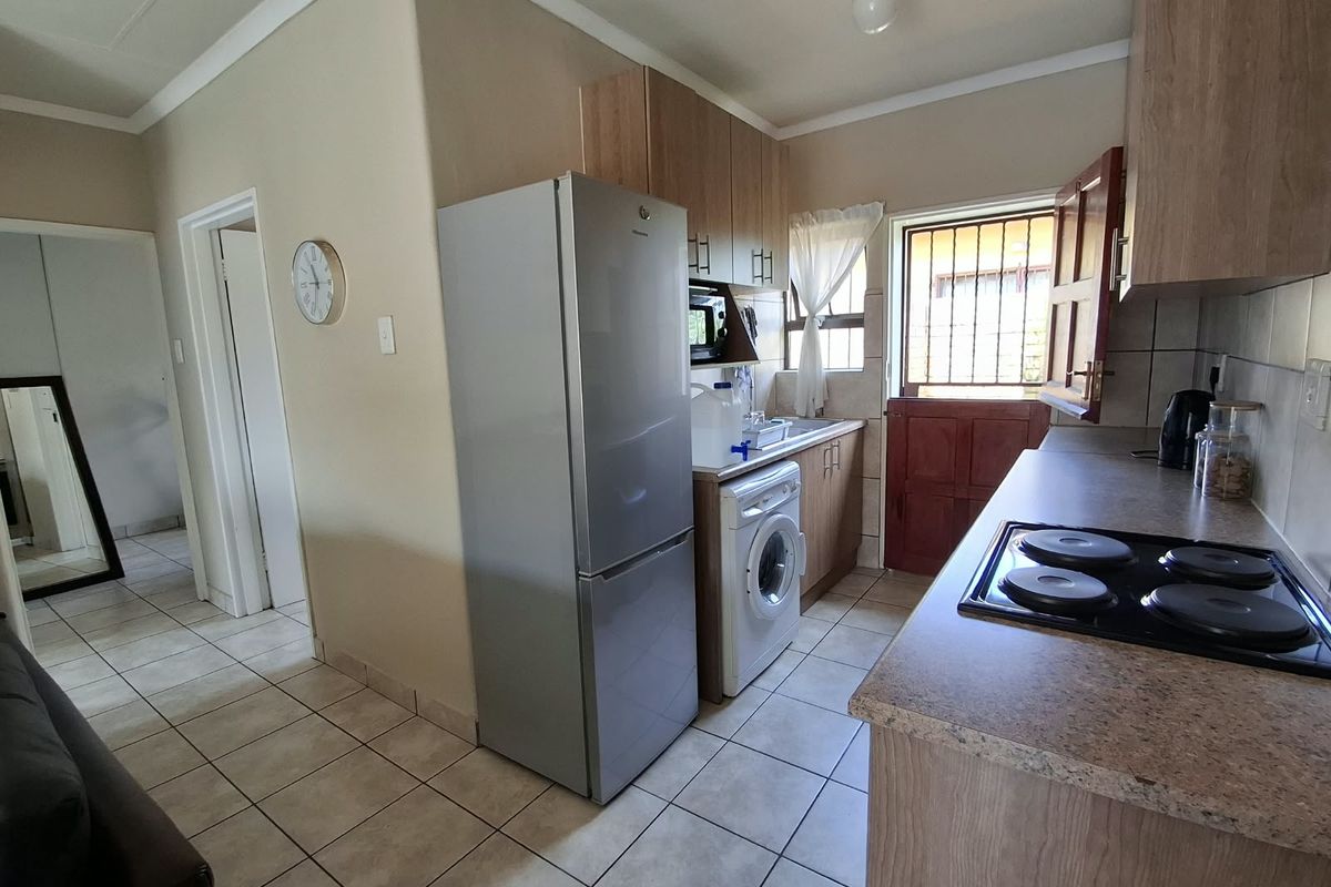 Functional kitchen featuring wood-look cabinetry, laminate countertops, an electric hob, and tiled flooring with direct access to the exterior via a stable door.