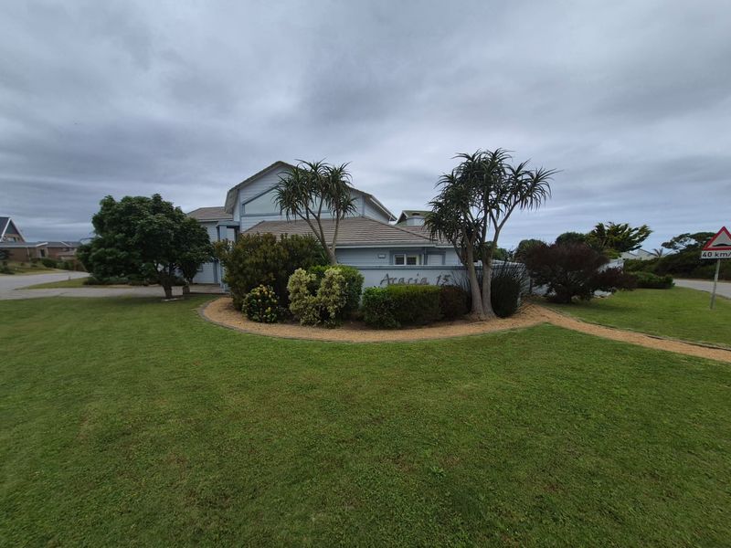 Front exterior view of the property featuring a well-maintained lawn, landscaped garden beds, and a tiled roof structure.