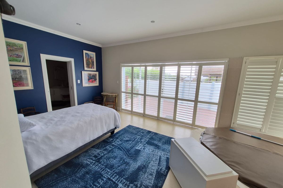 Spacious bedroom featuring tiled flooring, recessed lighting, and large sliding glass doors with plantation shutters providing direct access to the outdoor area.