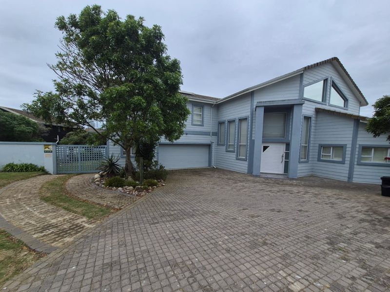 Front elevation of a multi-level house featuring timber cladding, a paved driveway, and a double garage with a gated side entrance.