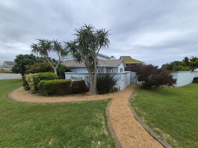 Front exterior view of the property featuring a landscaped garden, gravel pathway, and a boundary wall with signage.
