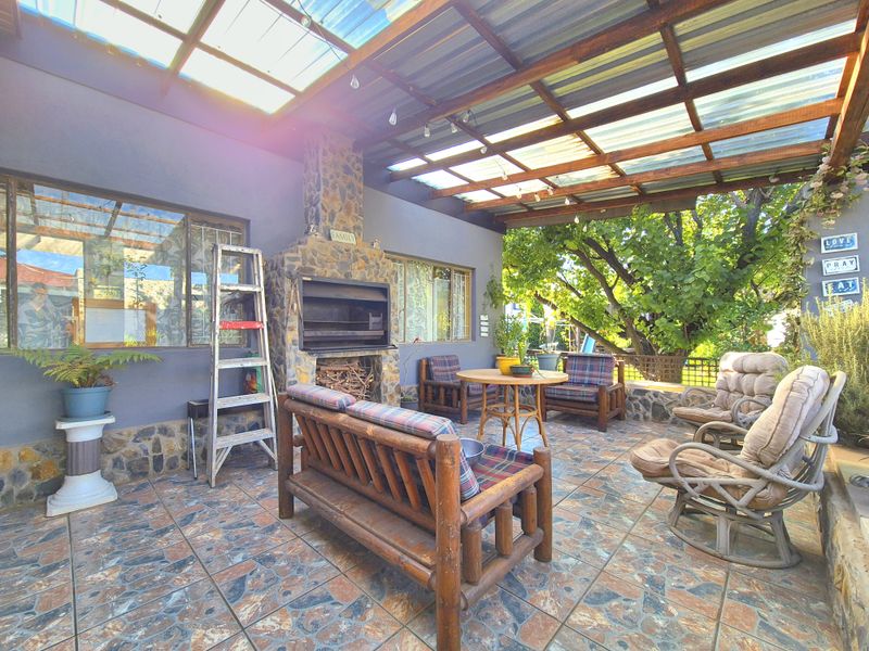 Covered outdoor patio featuring a built-in stone braai, tiled flooring, and a translucent roof, providing a functional space for outdoor entertaining.