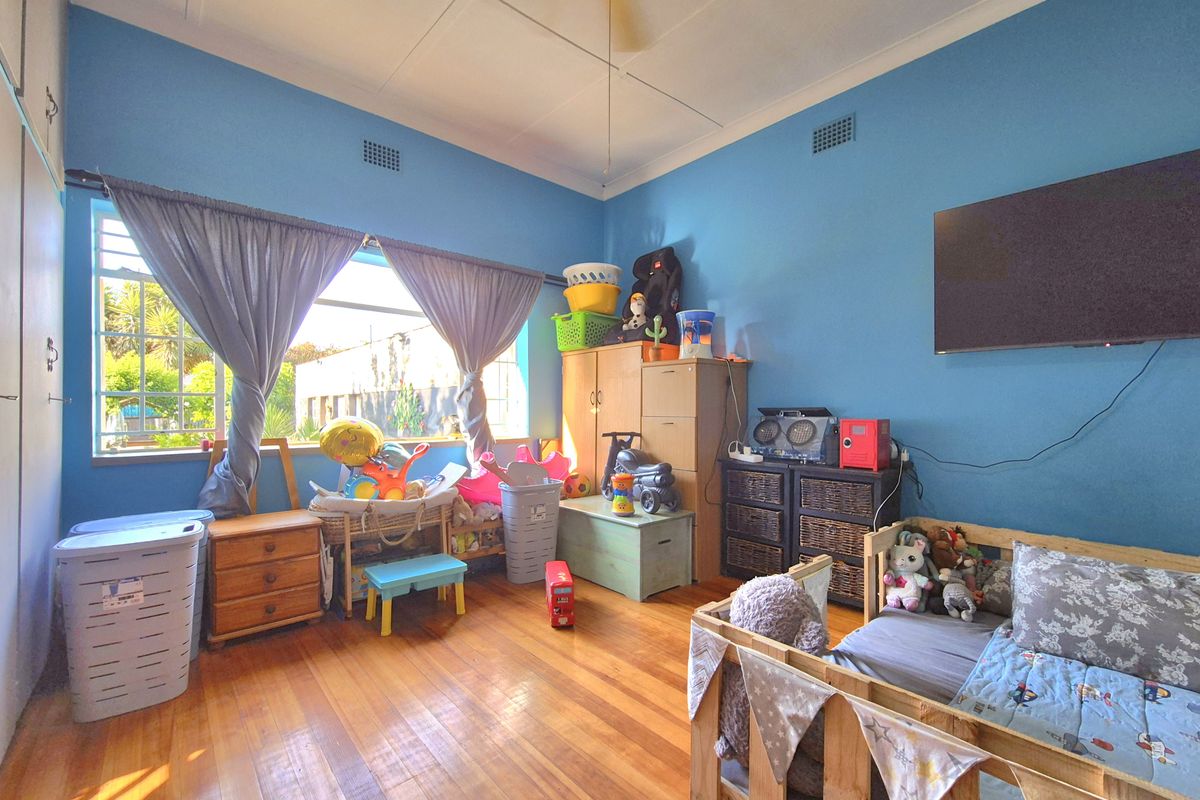 A bedroom featuring polished hardwood flooring, built-in storage cupboards, and a ceiling fan, finished with blue wall paint.