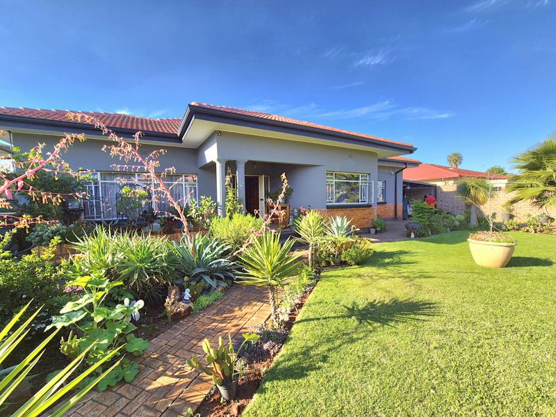 A well-maintained single-story house featuring a tiled roof, covered entrance porch, and a neatly landscaped front garden with a brick paved walkway.