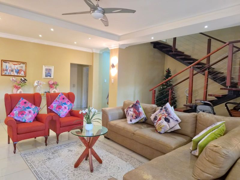 Spacious living area featuring tiled flooring, recessed lighting, a ceiling fan, and an open-plan staircase with timber treads and a modern wire balustrade.