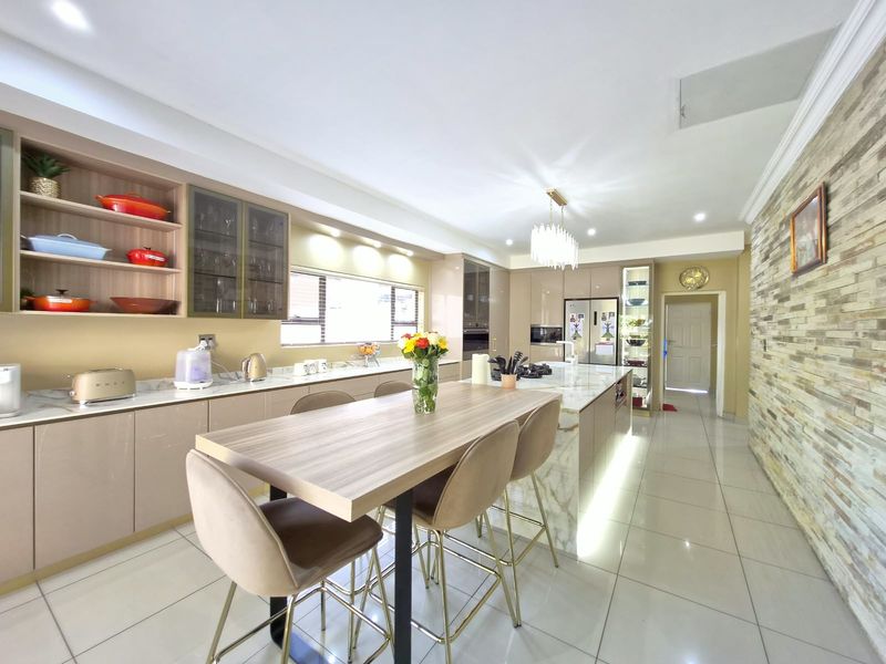 Modern, well-appointed kitchen featuring sleek cabinetry, a large stone-topped island with breakfast bar, integrated appliances, and a striking stone feature wall.