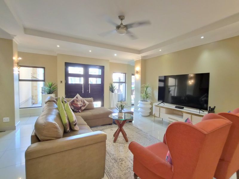Spacious living room featuring tiled flooring, recessed ceiling with downlights, a ceiling fan, and a double door entrance.