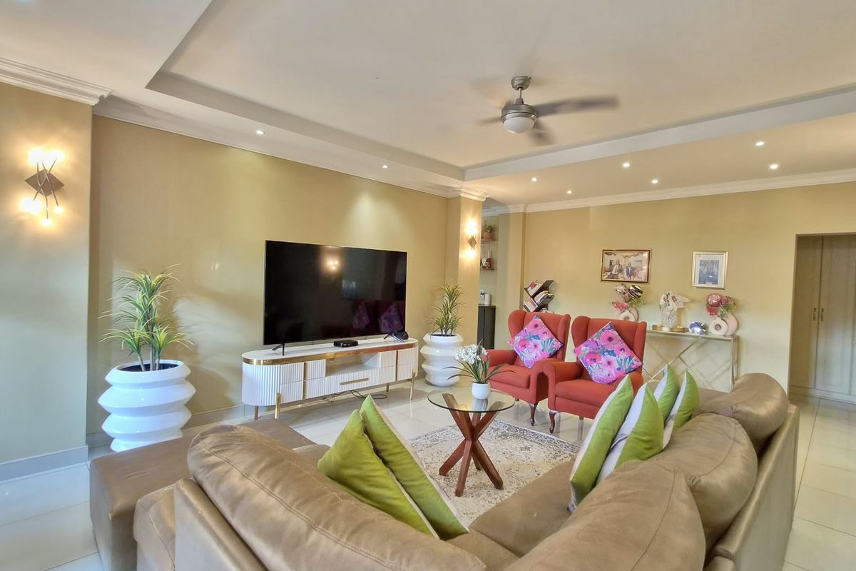 Spacious living room featuring a recessed ceiling with downlights, a ceiling fan, wall sconces, and neutral tiled flooring.