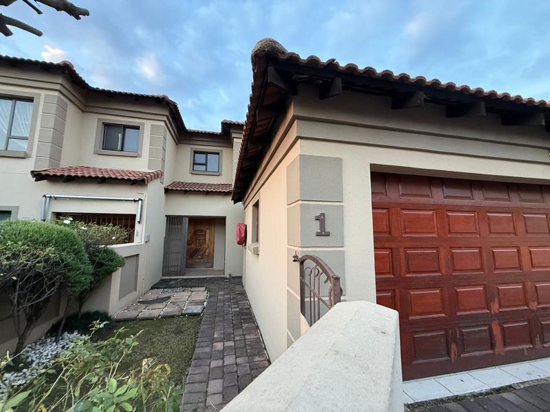 Front elevation of a townhouse featuring a paved walkway, timber garage door, and traditional tiled roof architecture.