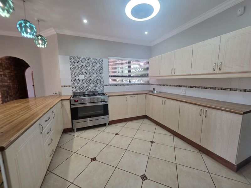 A clean and functional kitchen featuring light wood-finish cabinetry, laminate countertops, a stainless steel gas stove, and decorative tile backsplash accents.