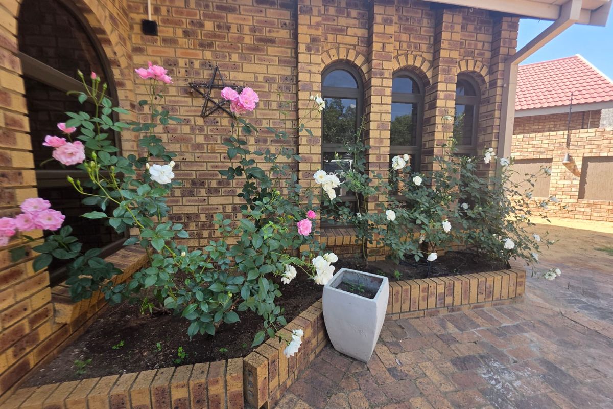 A well-maintained rear exterior featuring face brick walls, arched windows, and a paved patio area with a built-in brick planter.