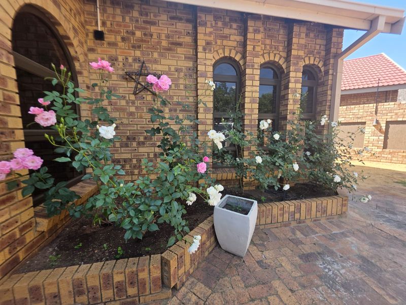 A well-maintained rear exterior featuring face brick walls, arched windows, and a paved patio area with a built-in brick planter.