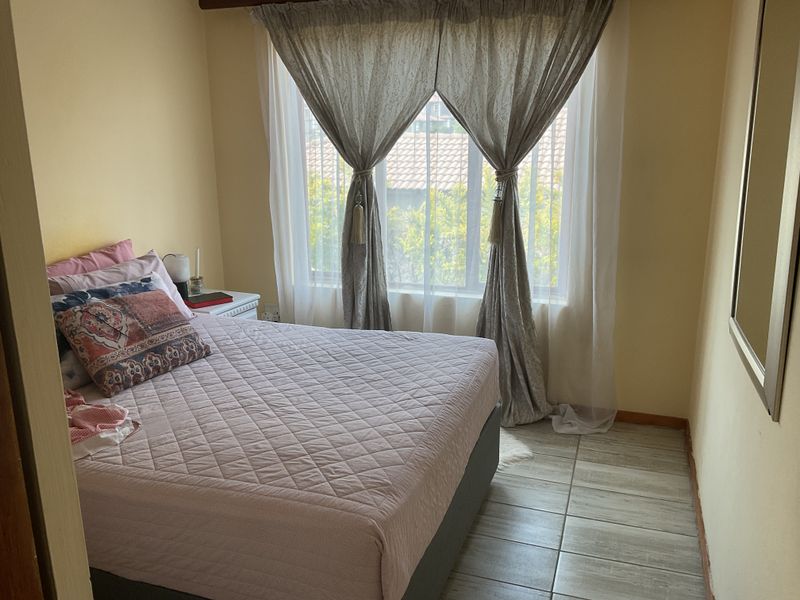 A standard bedroom featuring tiled flooring and a large window that allows for natural light.