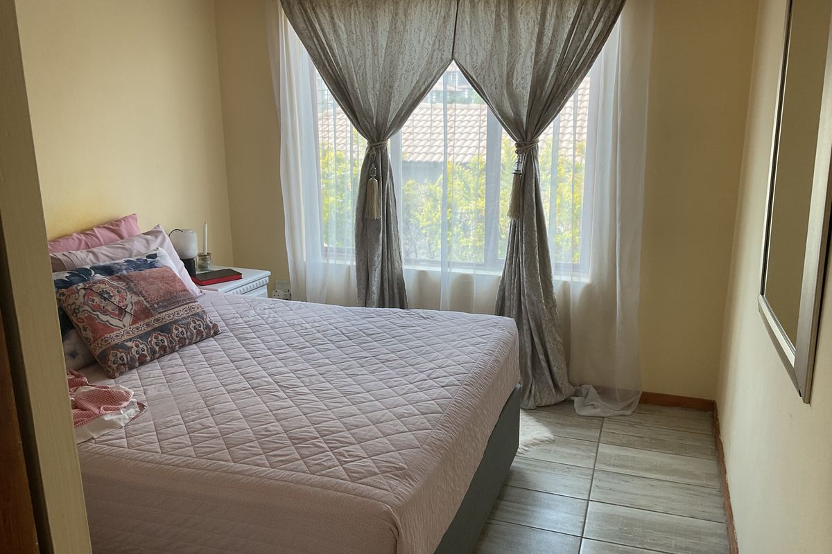 A standard bedroom featuring tiled flooring and a large window that allows for natural light.