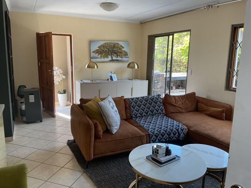 A living room featuring tiled flooring, a sliding glass door leading to the patio, and neutral wall finishes.