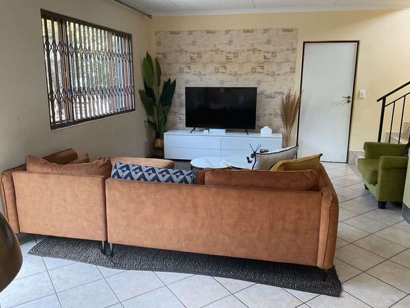 A comfortable living room featuring tiled flooring, a security gate on the window, and a decorative accent wall.