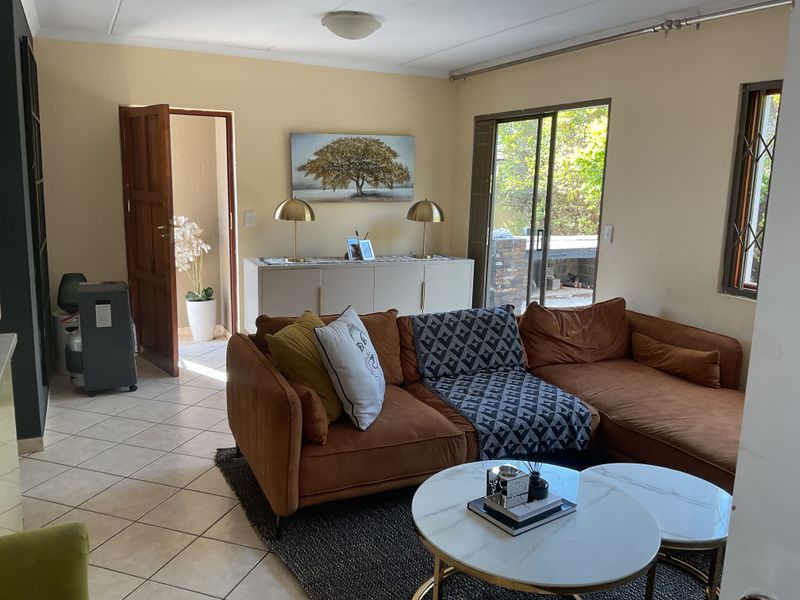 A comfortable living room featuring tiled flooring and a sliding glass door that provides direct access to the outdoor patio area.