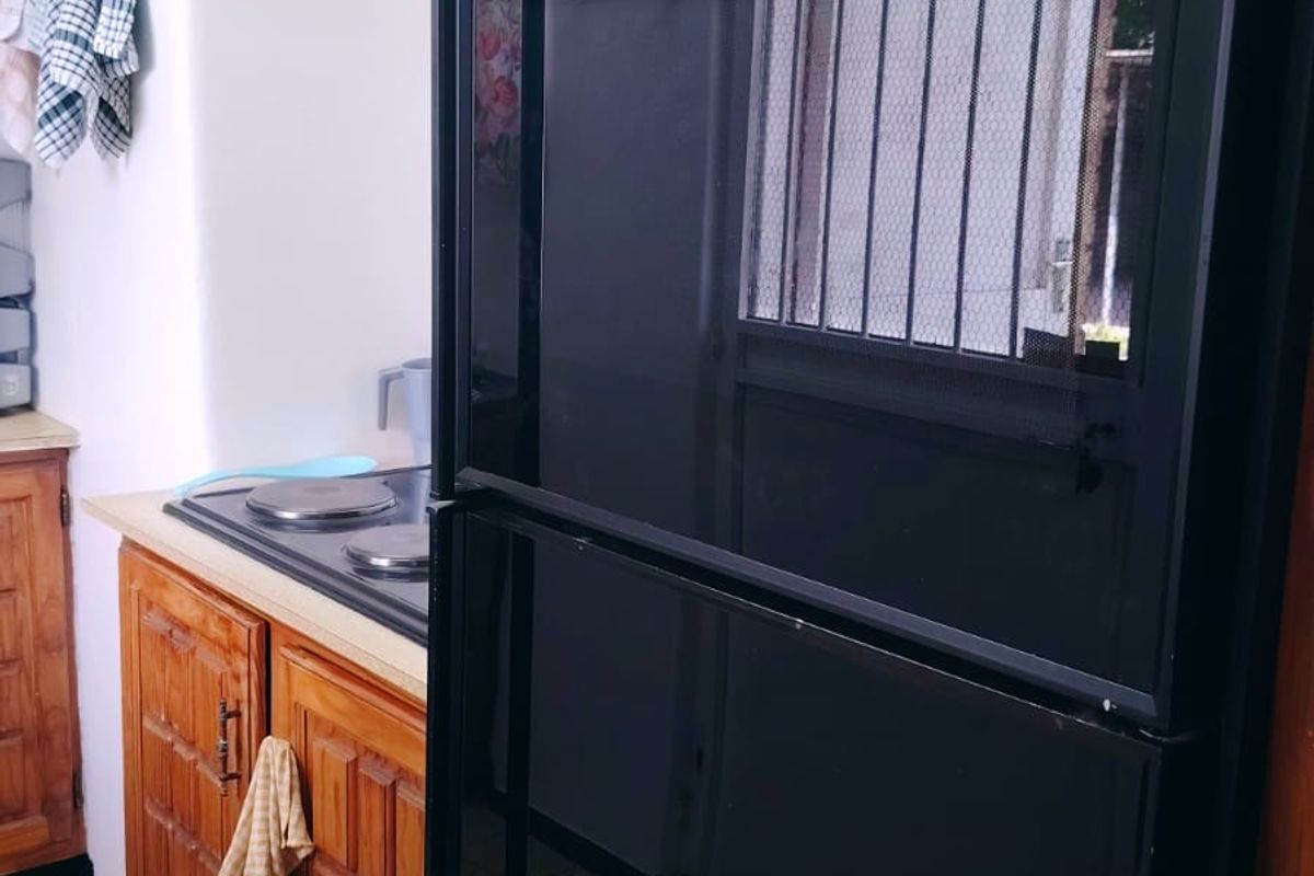 A kitchen area featuring traditional wooden cabinetry, a built-in oven, and an electric hob with tiled flooring.