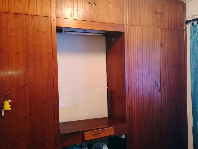 Bedroom featuring extensive floor-to-ceiling built-in wooden cabinetry with an integrated vanity desk and drawer unit.