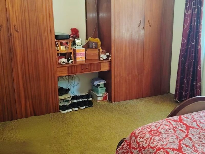 Bedroom featuring extensive built-in wooden cabinetry with an integrated vanity and a ceiling fan, finished with carpeted flooring.