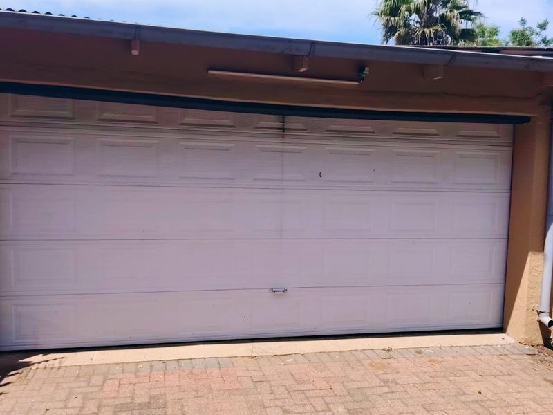 A single-width garage featuring a white sectional door and paved driveway access.