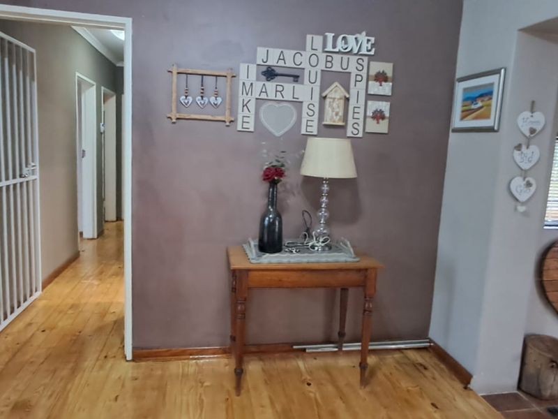 A hallway featuring timber flooring and an exposed brick wall section, providing access to other areas of the home.