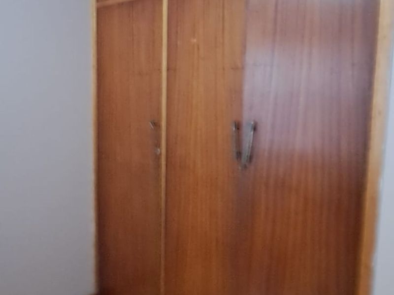A bedroom featuring built-in wooden cupboards and timber flooring, offering a neutral space ready for personalization.
