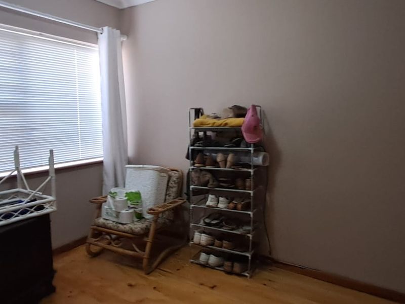 A bedroom featuring timber flooring, a built-in cupboard, and venetian blinds, offering a functional space with natural light.