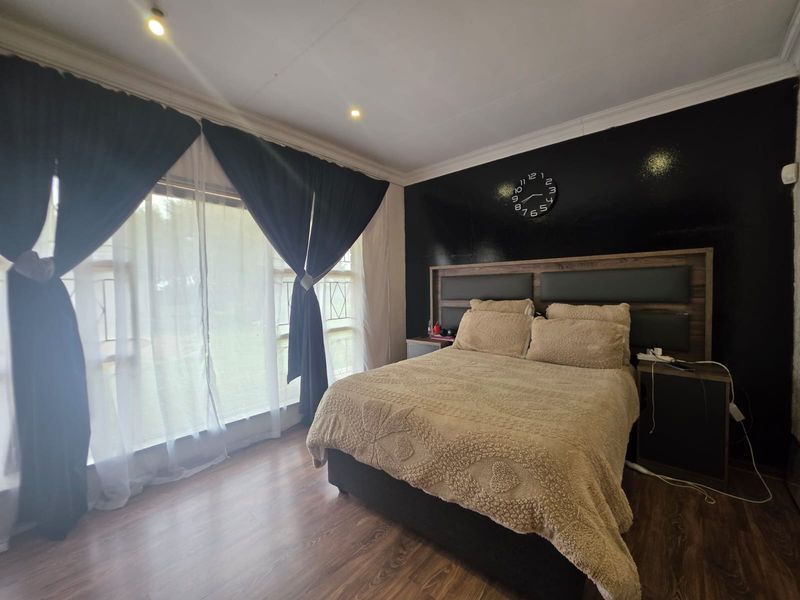 A well-maintained bedroom featuring laminate flooring, recessed downlighting, and decorative cornicing, creating a comfortable and modern living space.