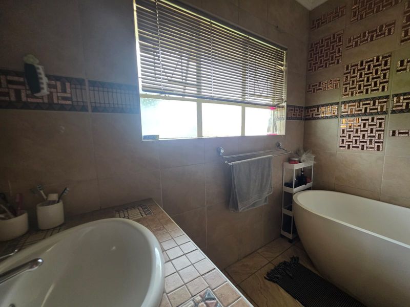 A functional bathroom featuring a freestanding bathtub, tiled vanity with a drop-in basin, and decorative wall tiling.