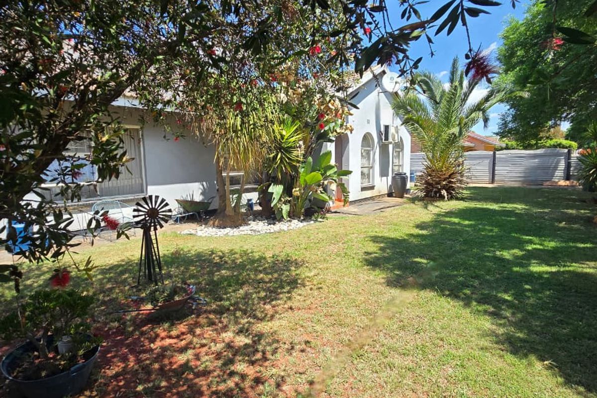 A spacious rear garden featuring a well-maintained lawn, mature trees, and perimeter fencing, providing a private outdoor space.