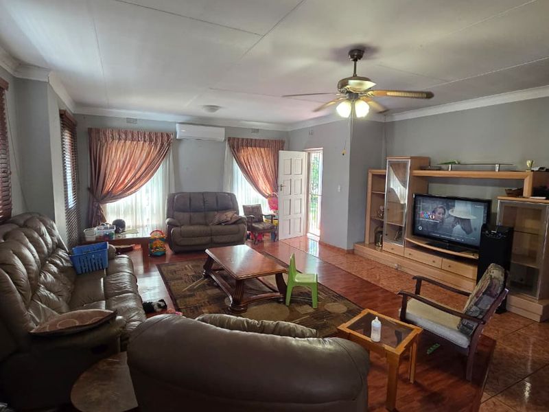 Spacious living room featuring tiled flooring, a ceiling fan, split-system air conditioning, and a built-in entertainment unit.