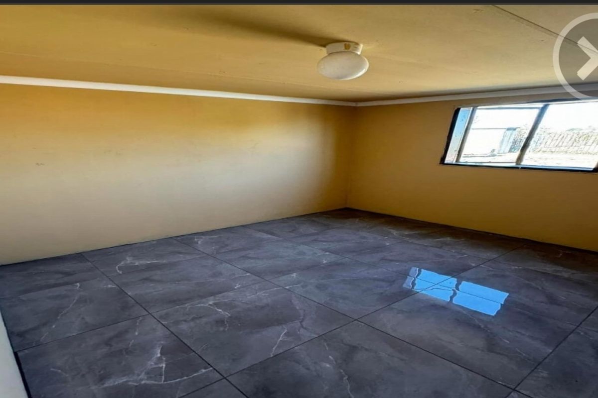 An empty bedroom featuring dark grey marble-look floor tiles, neutral walls, and a simple ceiling light fixture.