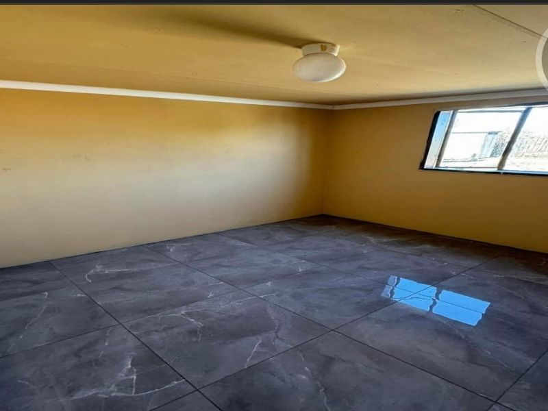 An empty bedroom featuring dark grey marble-look floor tiles, neutral walls, and a simple ceiling light fixture.