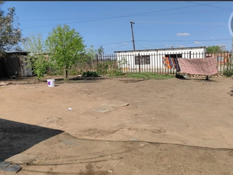 A spacious rear yard area featuring metal perimeter fencing and an outbuilding, offering significant potential for landscaping and outdoor development.