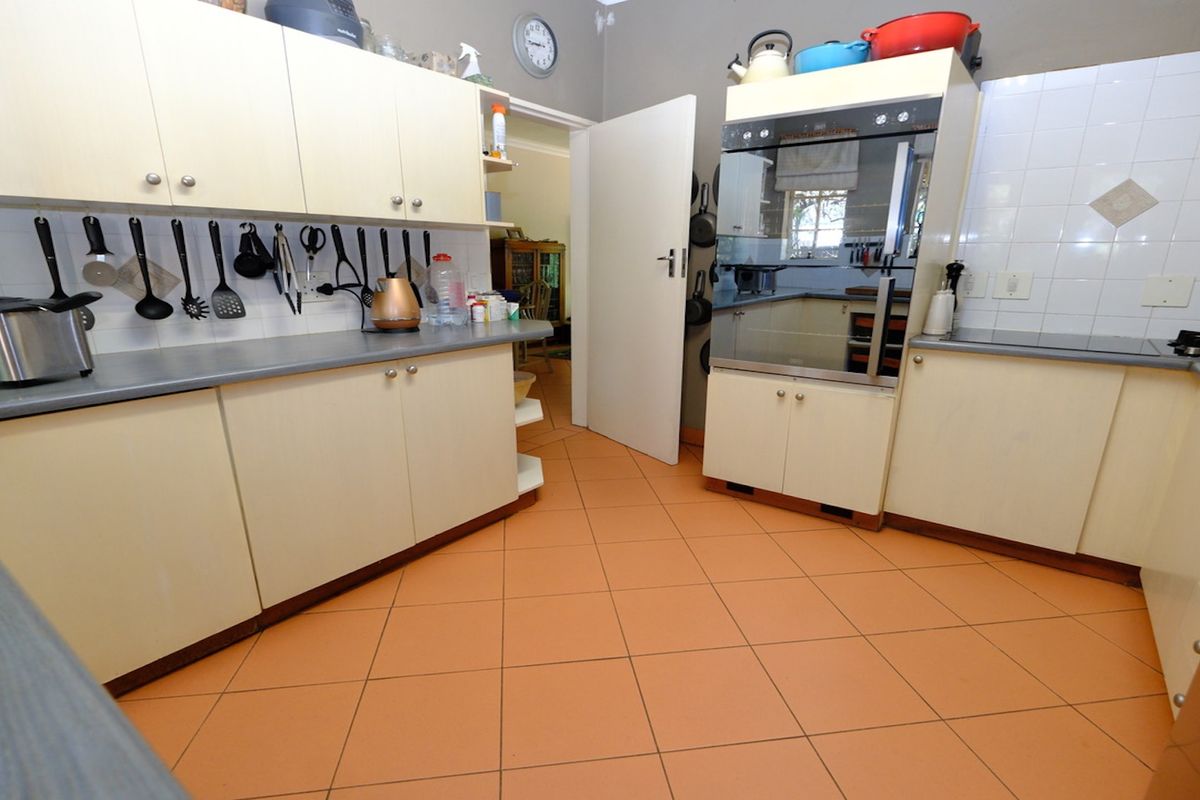 A functional kitchen featuring built-in cabinetry, laminate countertops, a built-in oven, and a ceramic hob with tiled flooring and backsplash.