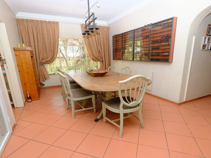 A dining room featuring terracotta floor tiles, decorative coving, and an arched entryway, providing a functional space for family meals.
