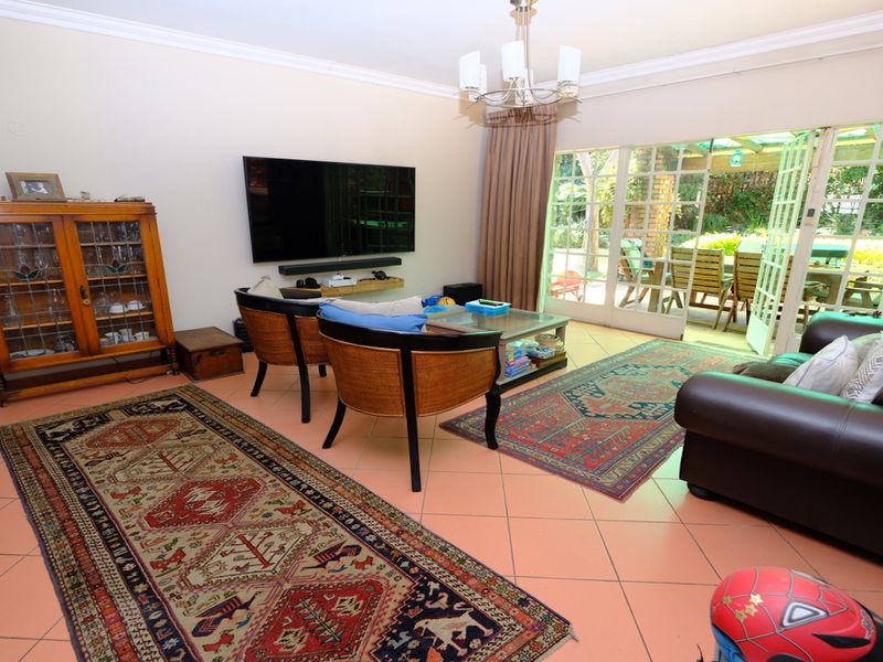 Spacious living room featuring tiled flooring, a central chandelier, and large sliding glass doors providing direct access to the outdoor patio area.