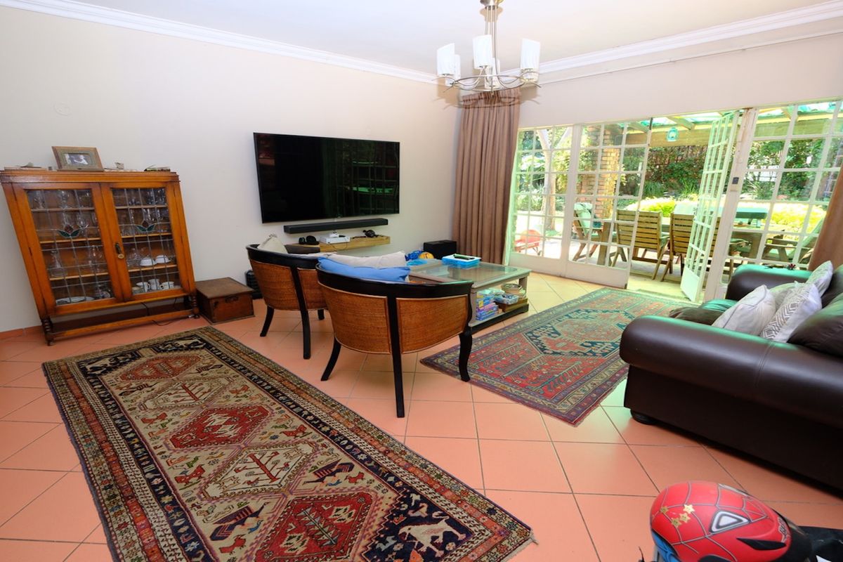 Spacious living room featuring tiled flooring, a central chandelier, and large sliding glass doors providing direct access to the outdoor patio area.