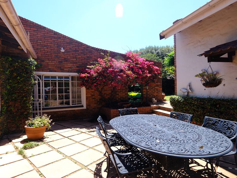 A private outdoor patio area featuring brick walls, paved flooring, and a raised planter, providing a charming space for outdoor dining and relaxation.